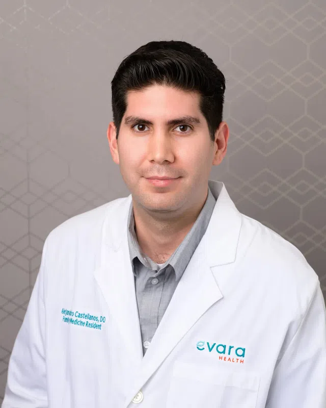 Professional portrait of a male doctor in white coat with Evara Health logo on gray patterned background