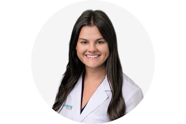 Smiling female doctor with long dark hair wearing a white lab coat on white background