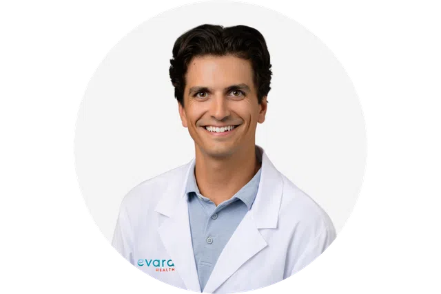 Smiling male healthcare professional wearing white lab coat over blue polo shirt on white background