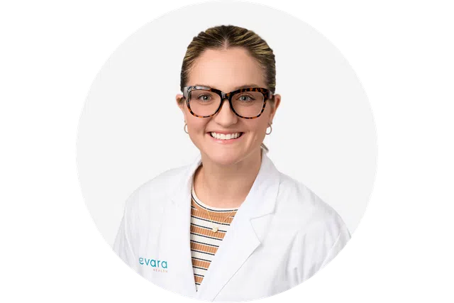Smiling woman in glasses and white medical coat with striped shirt against white background