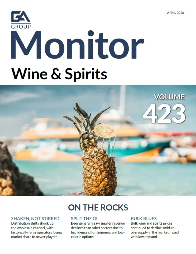 Pineapple drink with straws and umbrella on rocky shore with blurred boats and ocean background