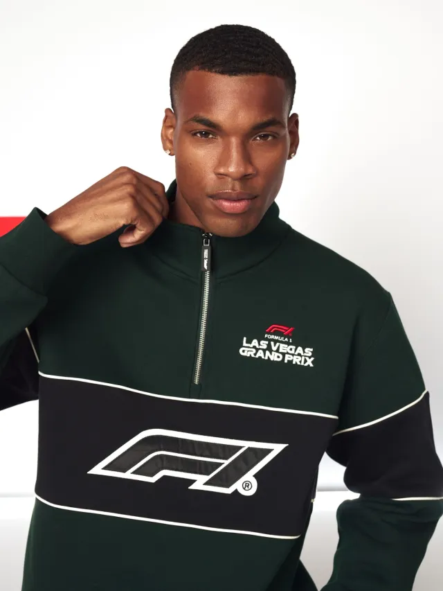 Man wearing black and green Formula 1 Las Vegas Grand Prix sweatshirt with logo and zipper collar.