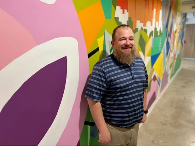 a man standing in front of a colorful wall