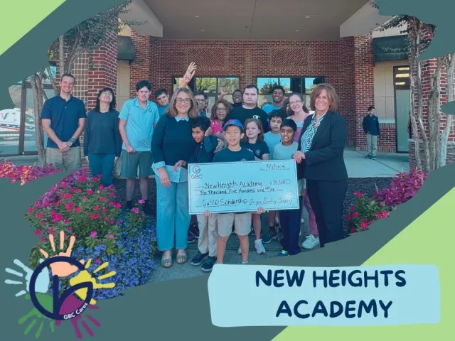 Group of students and adults holding a large check for New Heights Academy scholarship outside a brick building.