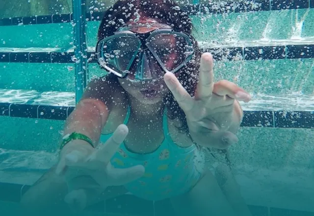 a person in a pool wearing goggles and a diving suit
