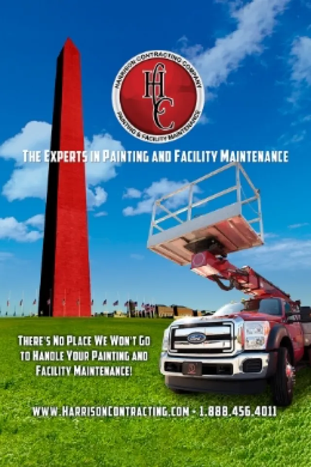 Red painted Washington Monument with maintenance truck and lift under a blue sky with clouds.