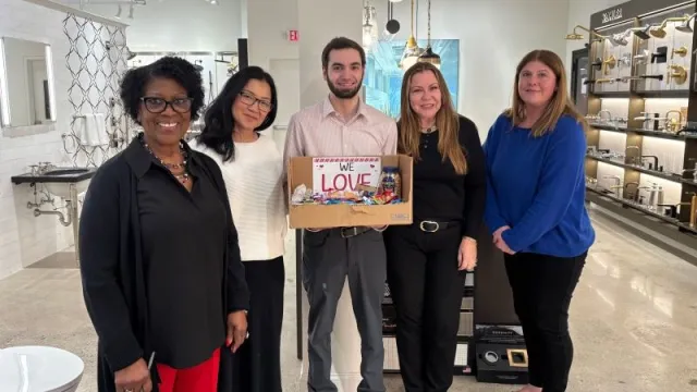 Group of five people posing with a colorful box, showcasing teamwork and collaboration in a bright retail setting.