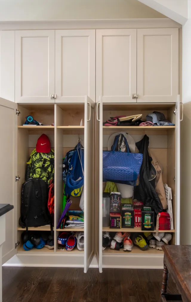 Open beige closet filled with backpacks, shoes, hats, bags, and household items neatly organized on shelves.