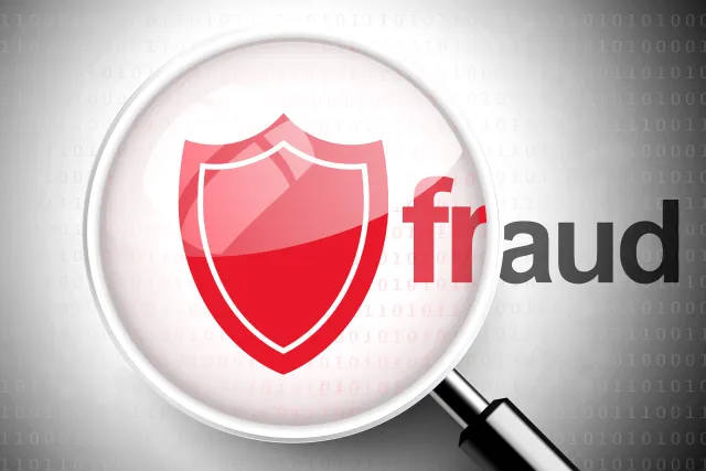 A magnifying glass highlighting a red shield symbol with the word 'fraud' against a binary code background.