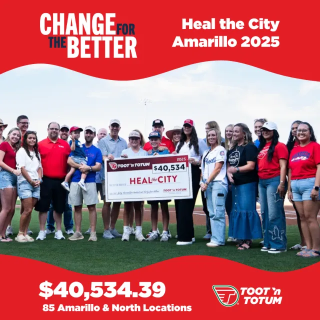 Group of diverse people holding $40,534 donation check for Heal the City Amarillo 2025 campaign on baseball field.