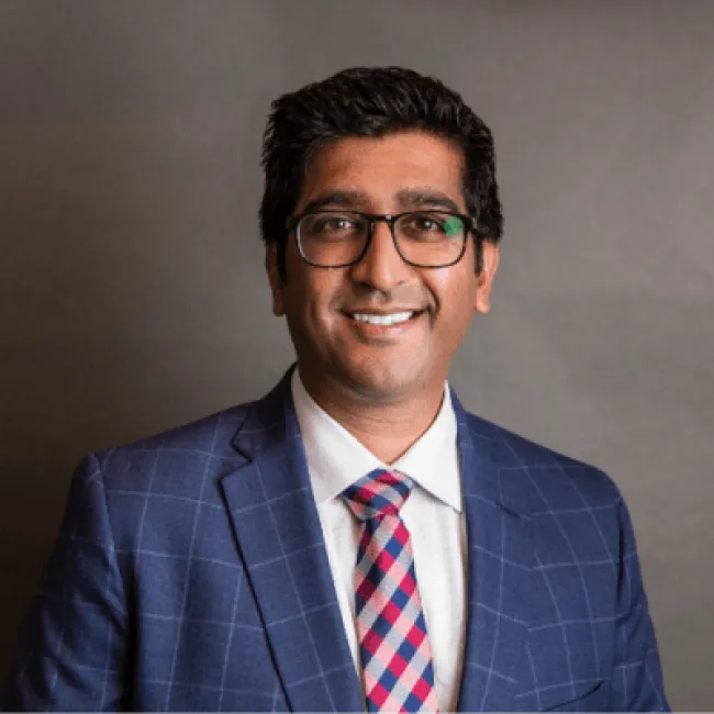 Jitesh Patel wearing glasses and a suit