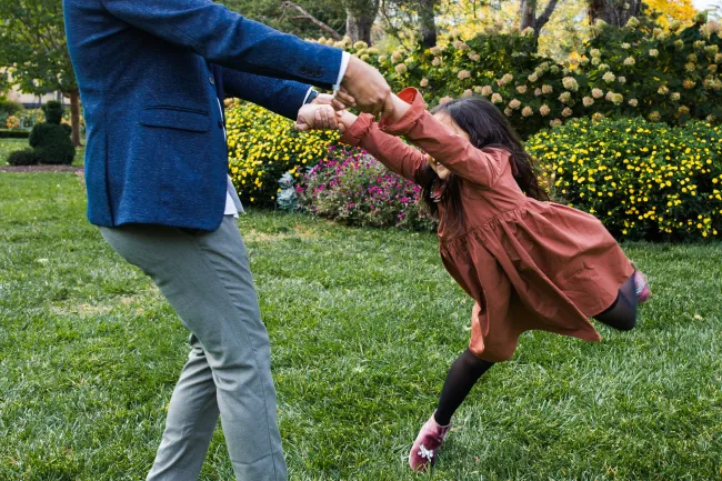 a person holding a child's hand in a grassy area