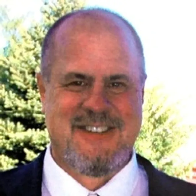a man wearing a suit and tie smiling at the camera