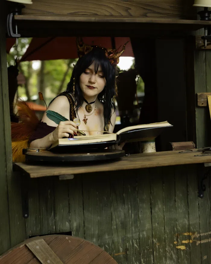 A costumed woman writes in a large ledger book