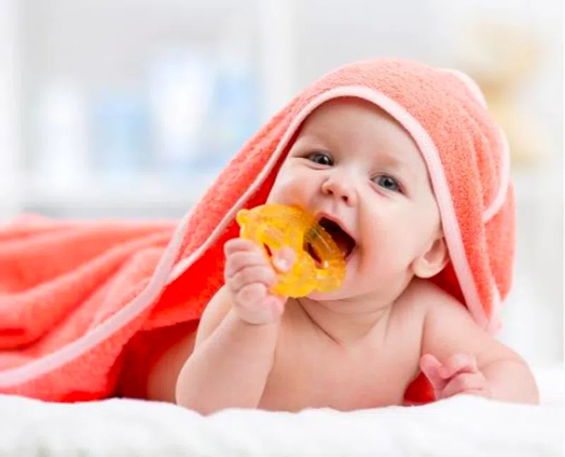 Smiling baby wrapped in a coral towel