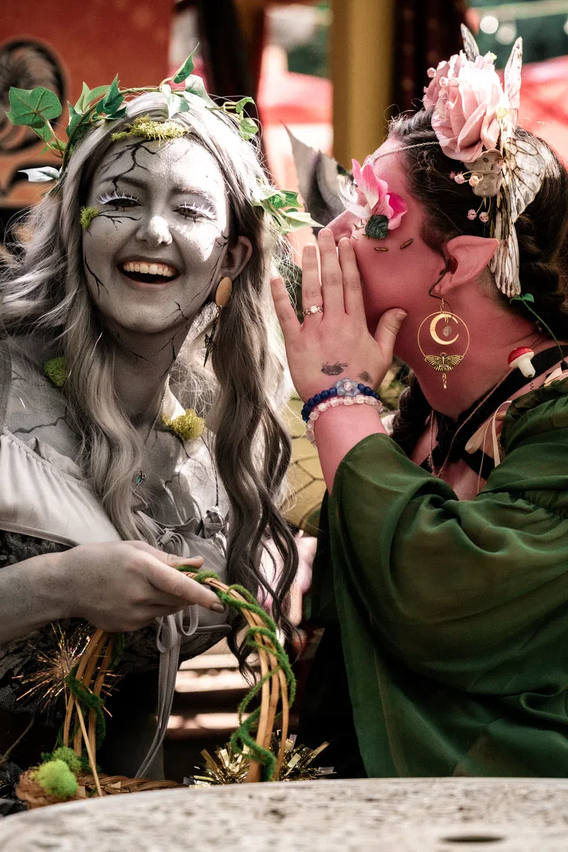 Two costumed guests sharing a whisper in the gardens of the Georgia Renaissance Festival