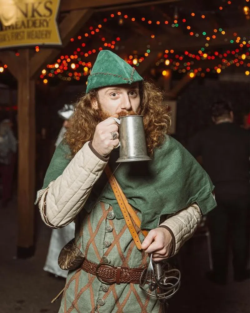 Robin Hood raising a pewter tankard under the lights at the Georgia Renaissance Festival
