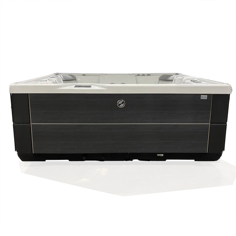 Modern rectangular hot tub with gray and black exterior panels and white interior seating on concrete floor.