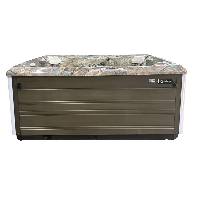 Outdoor hot tub with brown wood siding and marble-patterned interior with white headrests, isolated on black background