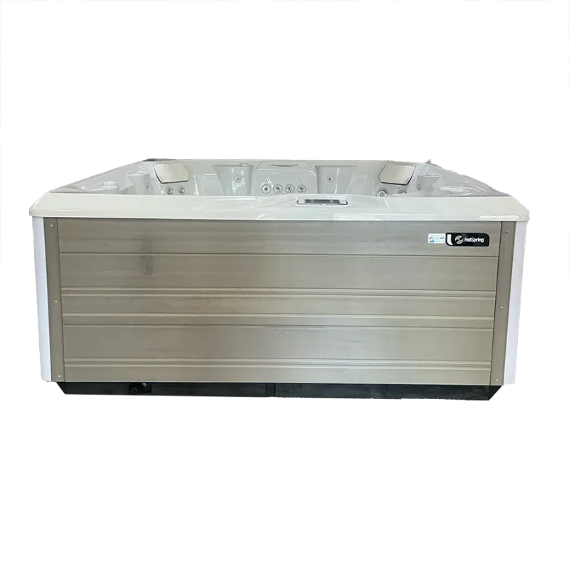 Luxury outdoor hot tub with multiple jets and padded headrests in a beige wood-paneled exterior
