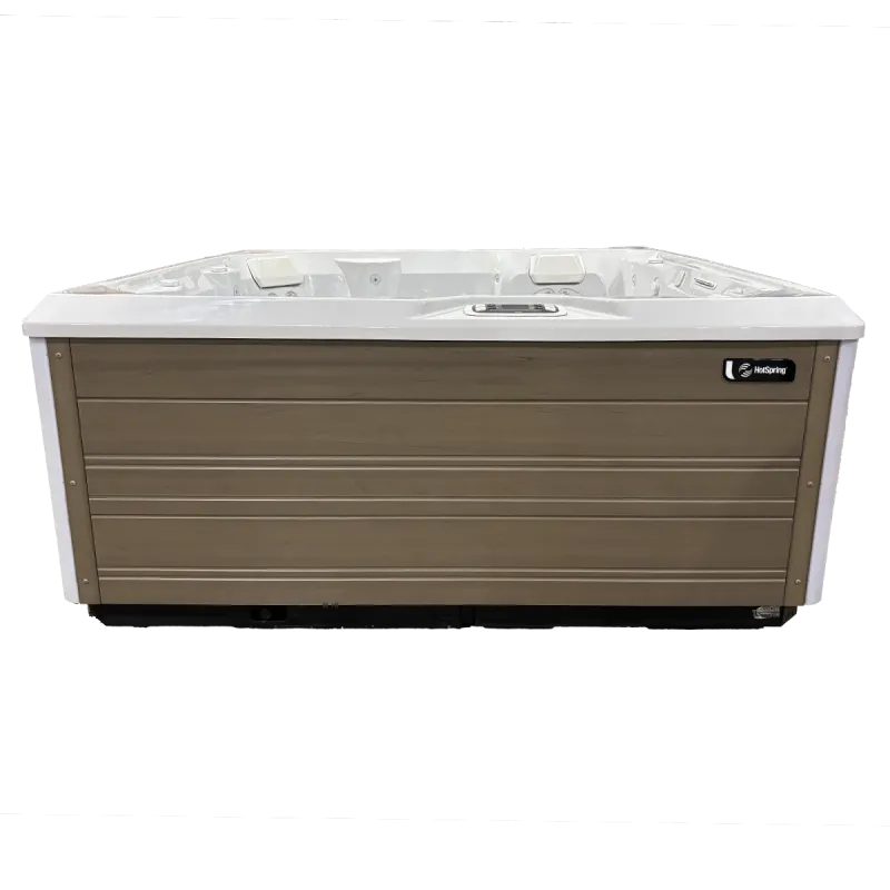 Rectangular outdoor HotSpring spa with white interior and brown wooden paneling, featuring built-in seats and controls.