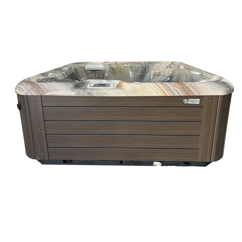 Brown outdoor hot tub spa with multiple jets, headrest, and control panel on wood-like exterior paneling.