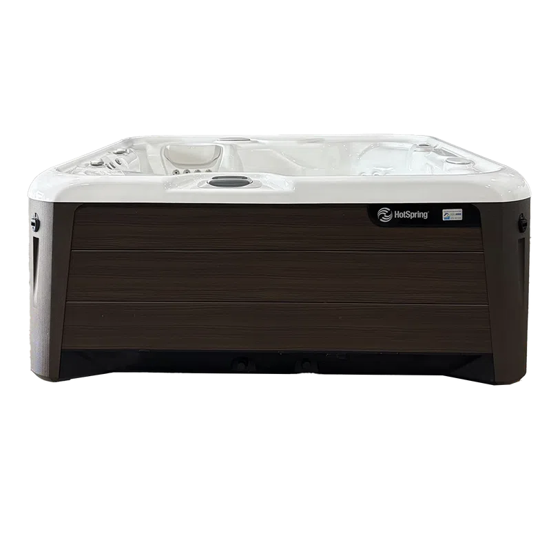 White interior and dark brown exterior HotSpring brand outdoor spa hot tub with seating and controls.