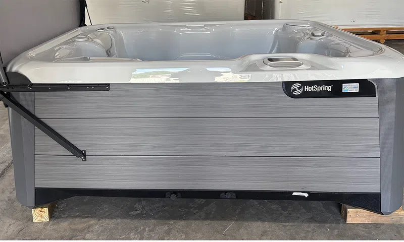 Side view of a modern HotSpring spa hot tub with gray exterior panels and white interior seating.