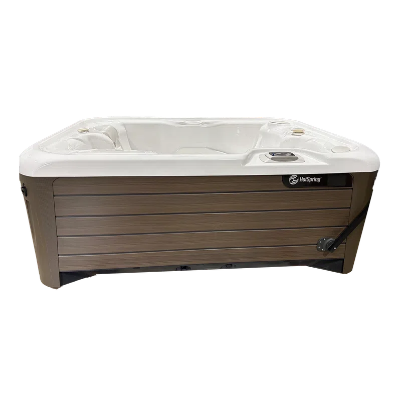 Outdoor HotSpring brand hot tub with white interior seating and wood-textured exterior panels.