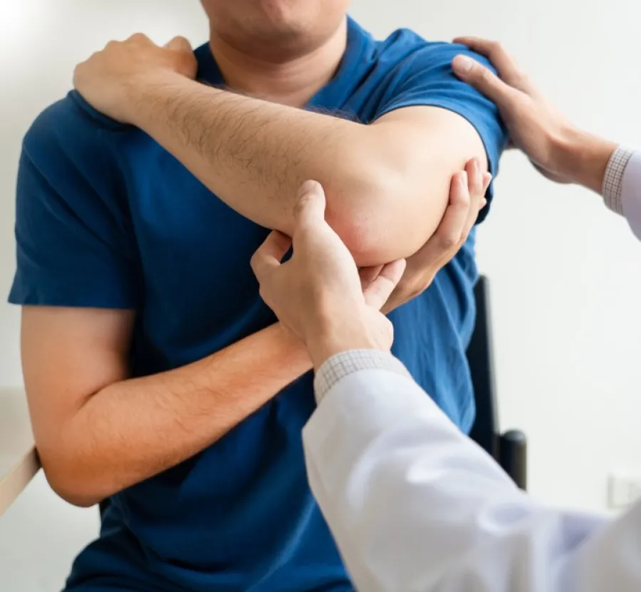 Doctor examining a patient's painful elbow, assessing injury in a clinical setting with focus on arm and hands.