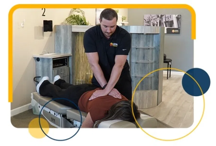 Chiropractor performing back adjustment on patient lying face down on treatment table in clinic.
