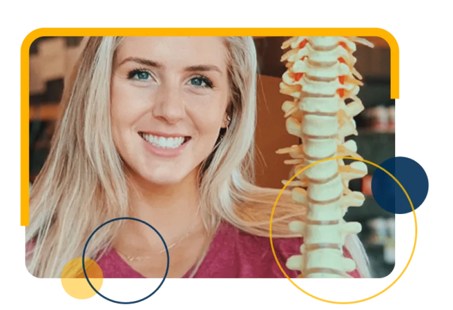 Smiling woman with blonde hair holding a spine model in a health or chiropractic setting