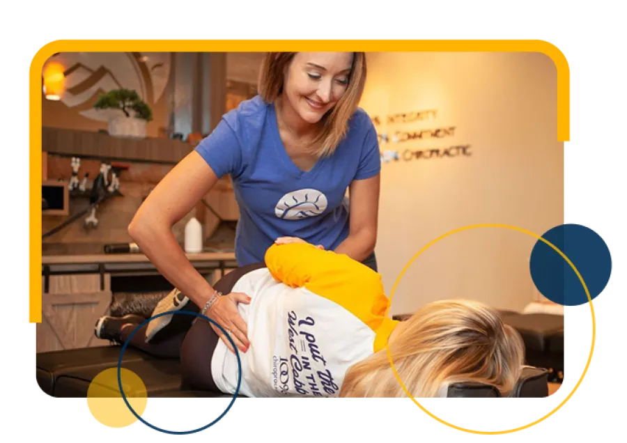 Chiropractor adjusts patient's lower back on treatment table in a modern clinic setting with warm lighting.
