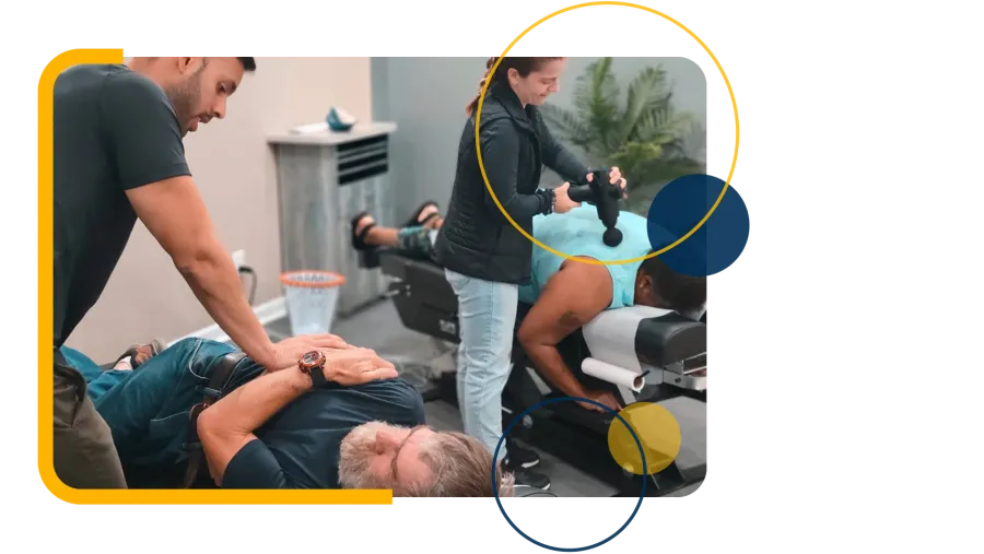 Man in gray shirt holding lower back, showing signs of back pain indoors with blurred background.