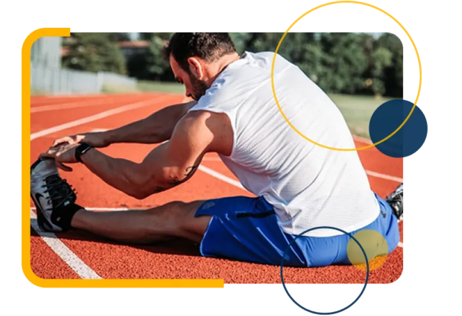 Athlete in white tank top and blue shorts stretching hamstrings on a running track before training.