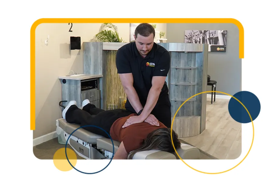 Chiropractor performs spinal adjustment on patient lying face down on treatment table in clinic.