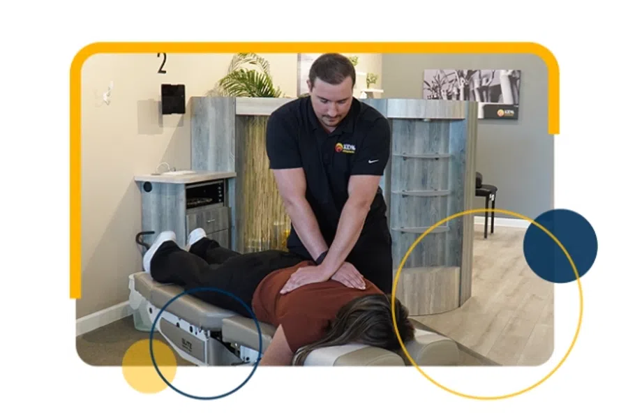Chiropractor performs spinal adjustment on patient lying face down on treatment table in clinic.