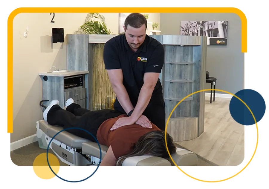 Chiropractor performing spinal adjustment on a patient lying face down on a treatment table in a clinic.