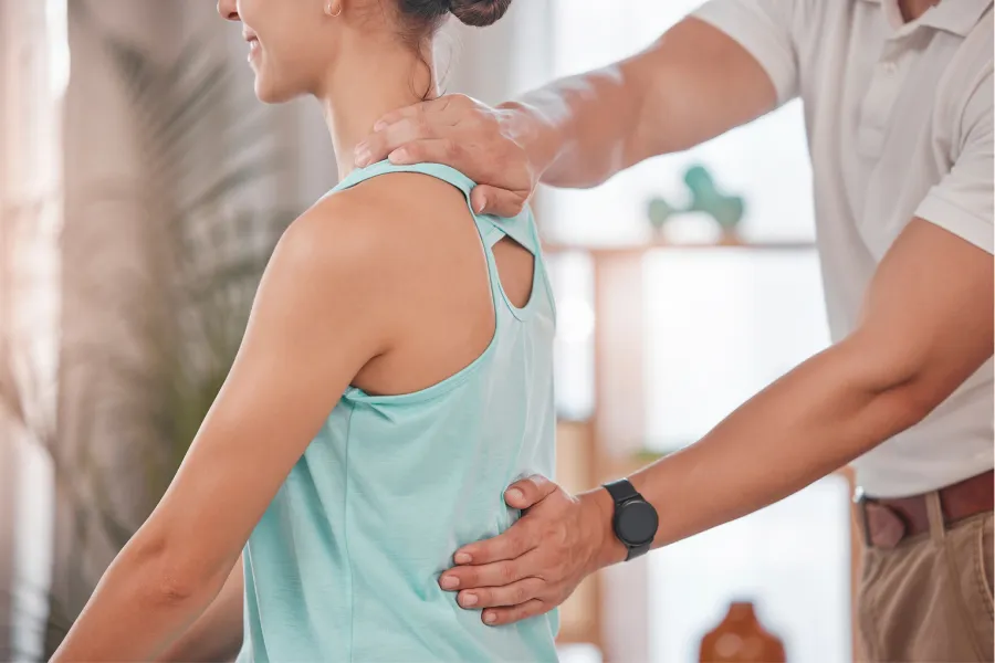 Doctor examining cervical spine and torso X-ray images on a large screen in medical office.