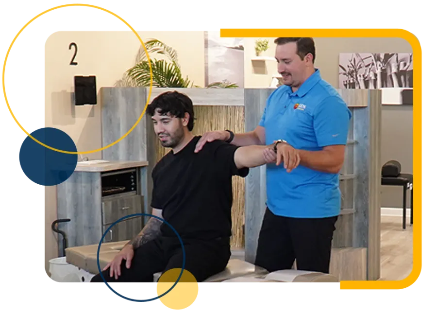 Physical therapist assisting a seated man with shoulder stretching exercise in a modern clinic room