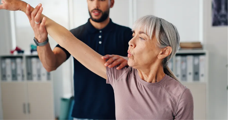 Chiropractor adjusting patient lying on treatment table in wellness clinic with colorful wall background.