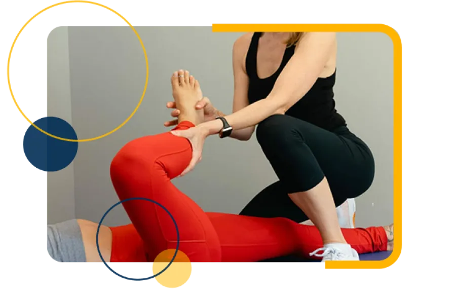 Physical therapist assists woman in red leggings with leg stretch during rehabilitation session.