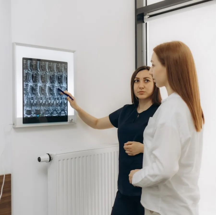 Doctor explaining spinal X-ray images to patient in a medical office with focused expressions