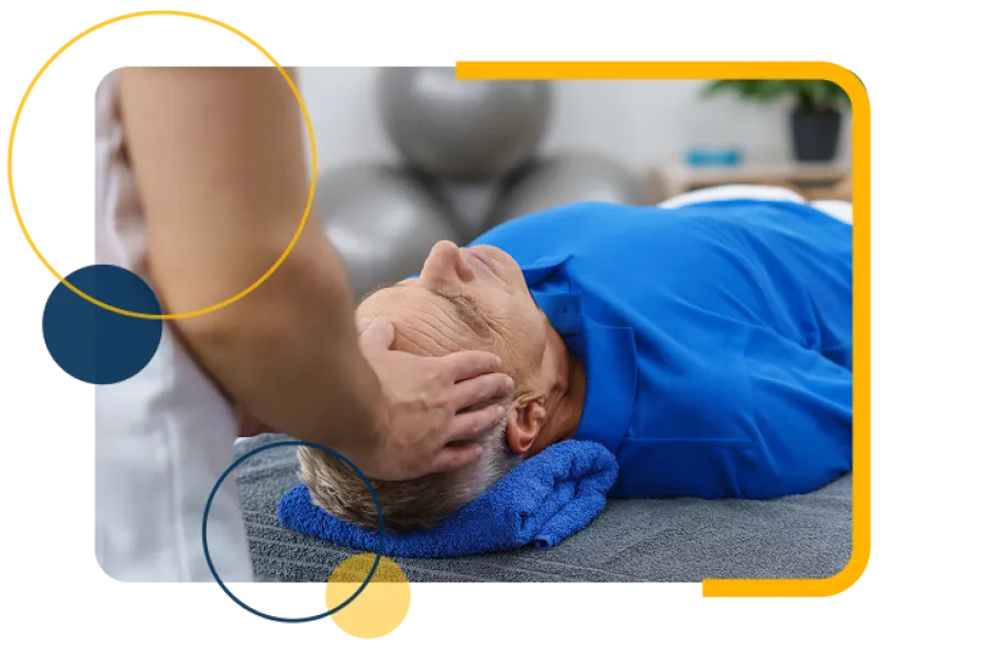 Therapist performing head massage on elderly man lying on massage table with towel support.