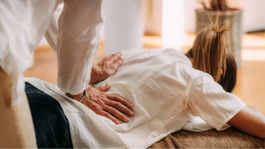 Hands giving a relaxing back massage on bare skin in a calm indoor setting.