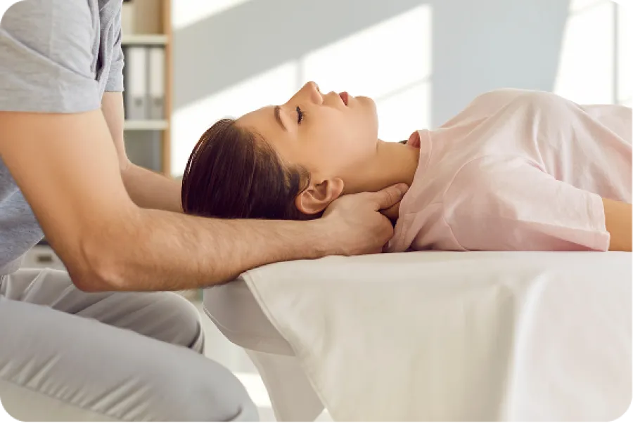 Therapist performing gentle neck massage on woman lying on a treatment table in a bright room.