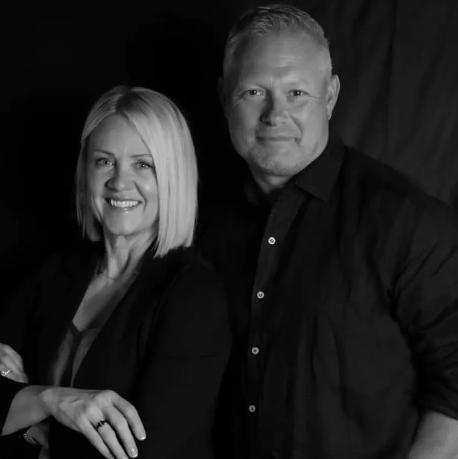Black and white portrait of a smiling mature man and woman standing close with confident expressions.