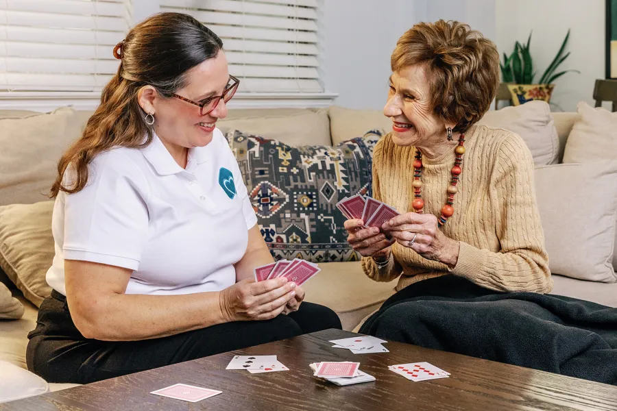 Two women enjoying a card game together, fostering connection and fun in a cozy living room setting.