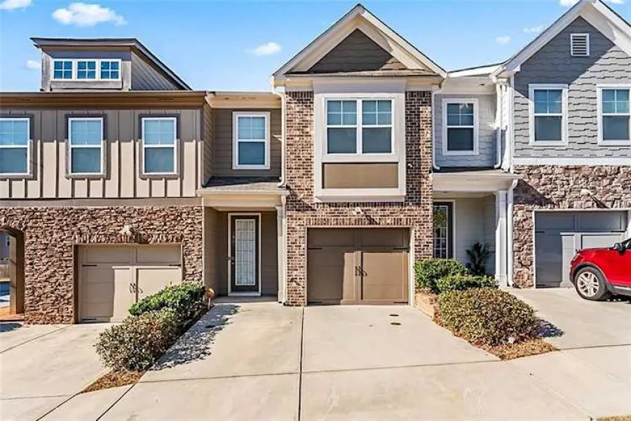 Modern townhouse in Lithonia, GA with brick and siding exterior, garage, driveway, and clear blue sky on a sunny day