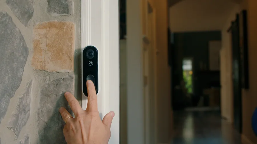 a hand touching a doorbell